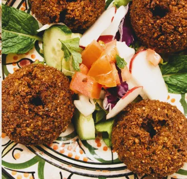 Falafel with chopped tomato, cucumber, radish and mint on a patterned ceramic plate