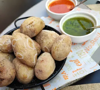 Papas arrugadas — small salt-crusted potatoes — in a black pan with bowls of red and green mojo